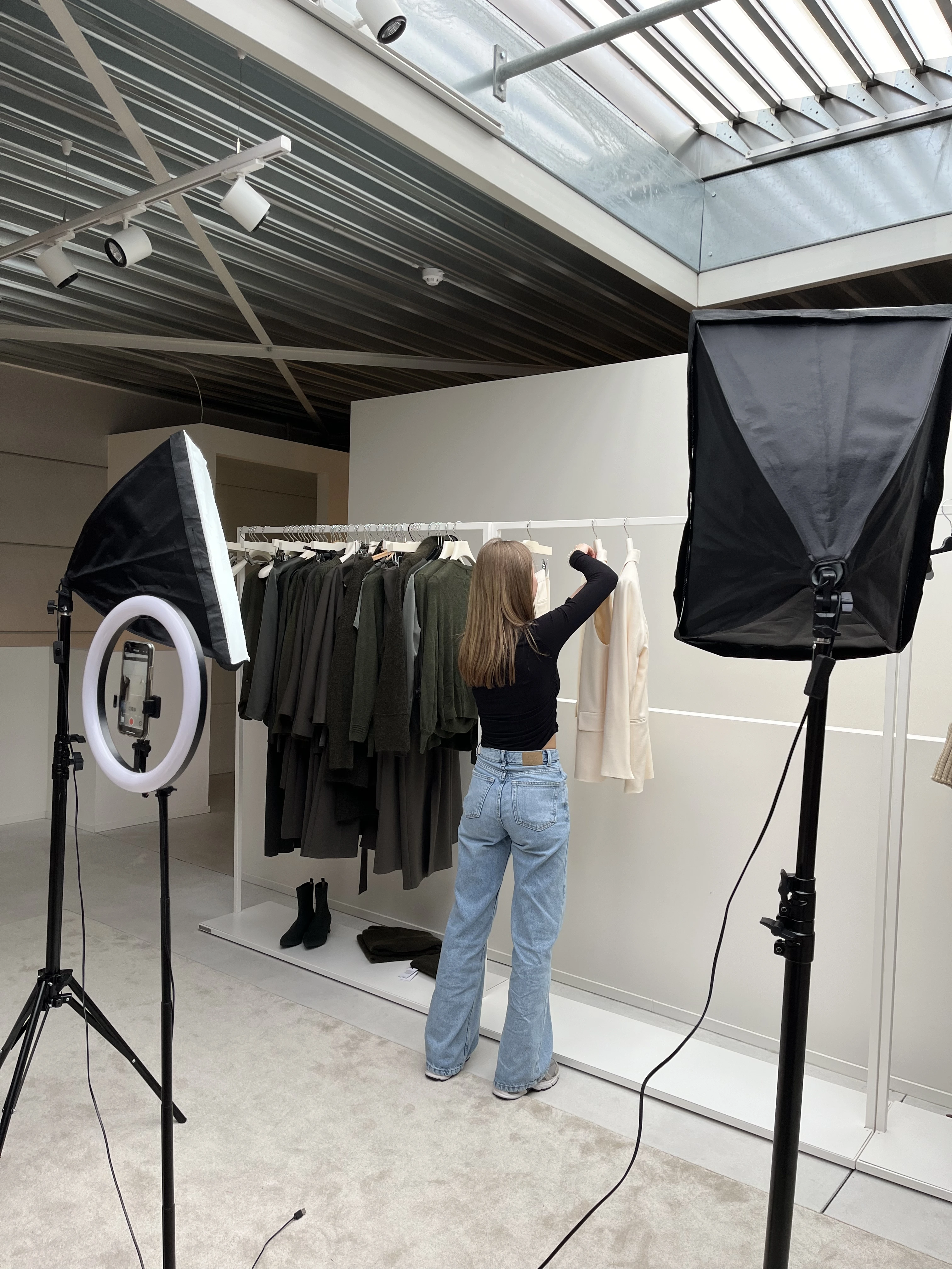 Meisje hangt kleren aan kapstok met een lichtsetting voor foto's te maken